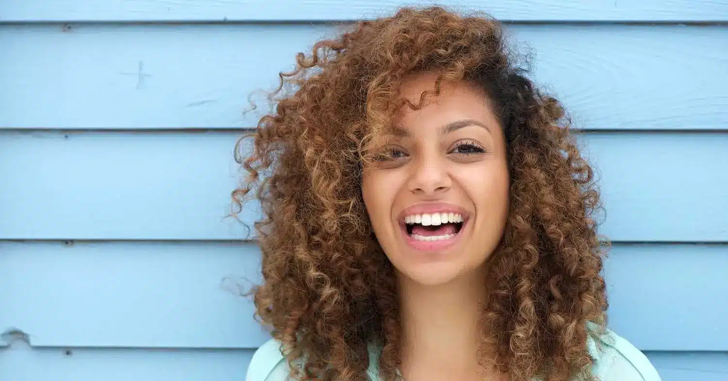 A woman smiling and leaning against a wall, representing confidence and hope after trauma counselling.
