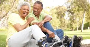 Senior couple putting on in line skates In park