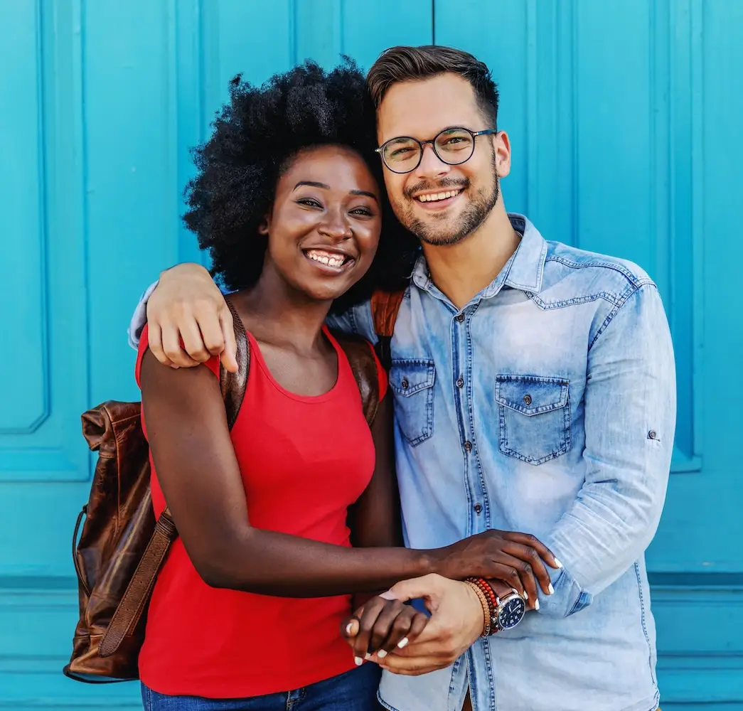 Young attractive multicultural couple in love standing outdoors and holding hands.