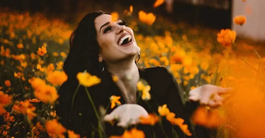 The image shows a woman in a field of flowers, empowered by managing her emotions