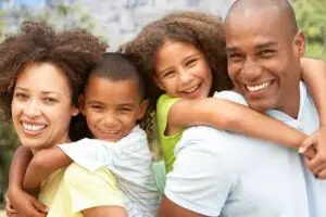 A happy couple outdoors carrying their children on their backs, symbolizing healing, resilience, and connection. The image represents the positive outcomes of therapy and relates to the topic “what is trauma counselling.