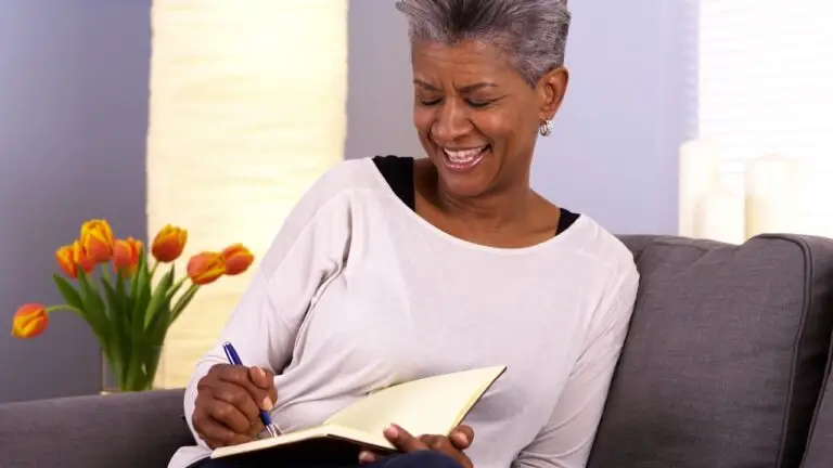 Woman sitting on a couch documenting what is the difference between trauma and complex trauma in a book.