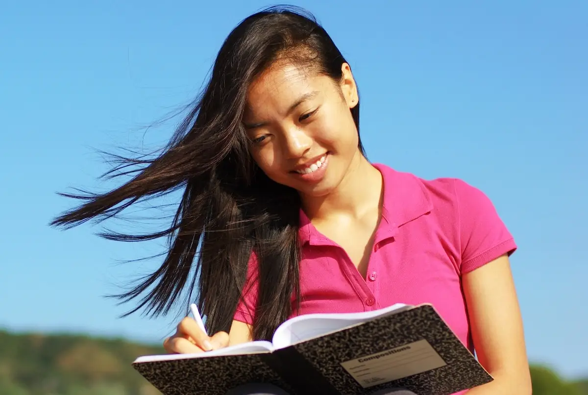 Outside in natural setting, a person journals about the benefits of IFS and EMDR for trauma recovery.