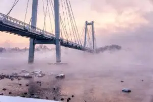 The bridge stretches into fog with a soft violet hue, symbolizing hope and connection in social justice in trauma therapy, even when outcomes are uncertain.