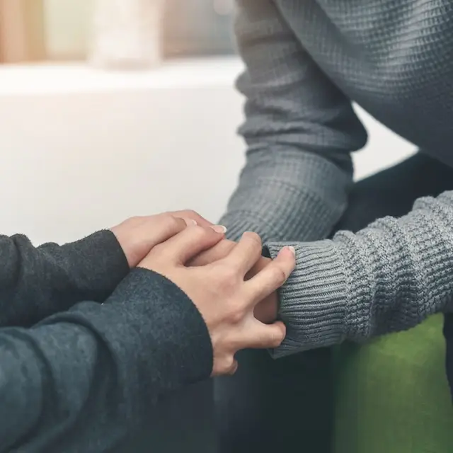 A counsellor's hand gently holding a client’s hand, symbolizing non-judgmental, personalized support and a trusting healing relationship.