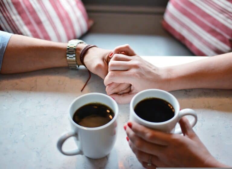 Two people holding hands in a coffee store, symbolizing healing relational trauma.