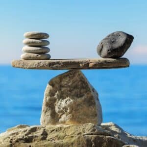 Balanced stone scale with the sea in the background, symbolizing fairness and balance in variable pricing tailored to individual needs.