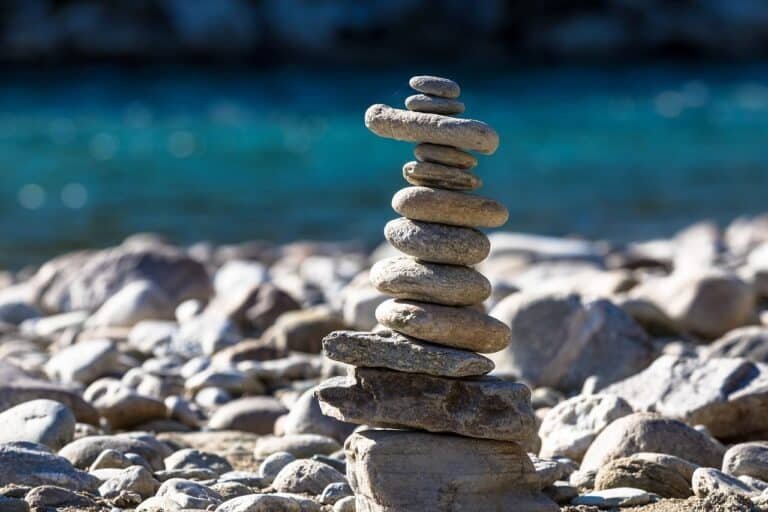 Balanced stones stacked on a riverbank, representing awareness and balance in responding to childhood trauma triggers in adulthood.