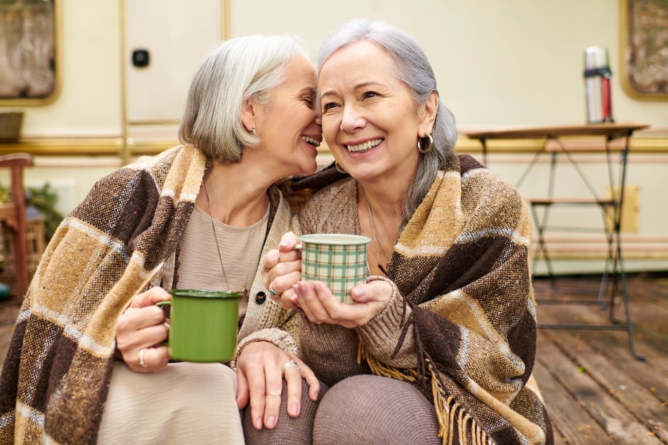Lesbian couple with coffee and blanket outdoors - healthy boundaries for adults with childhood trauma enable connection.