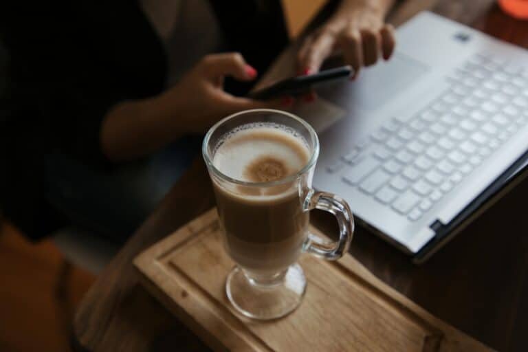 Individual in a coffee shop with their device and laptop, exploring the question: Can AI help heal trauma?