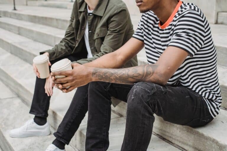 Two friends sitting on stairs, symbolizing healing of childhood trauma in adult relationships.