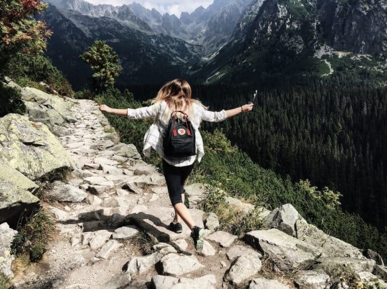Joyful person on a mountain trail, symbolizing the path of healing after understanding how childhood trauma affects the nervous system.