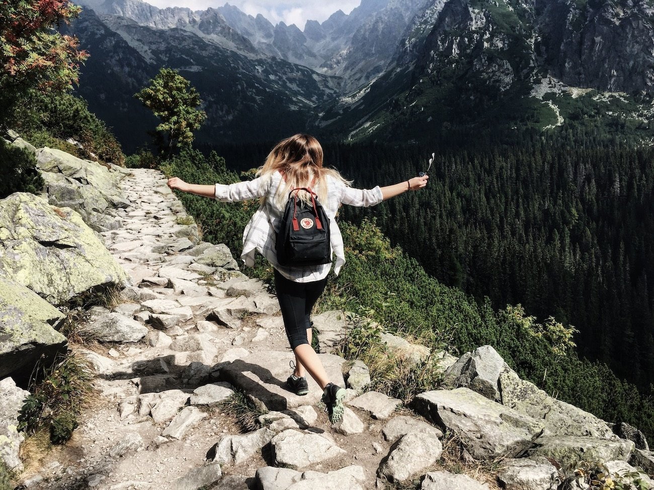 Joyful person on a mountain trail, symbolizing the path of healing after understanding how childhood trauma affects the nervous system.
