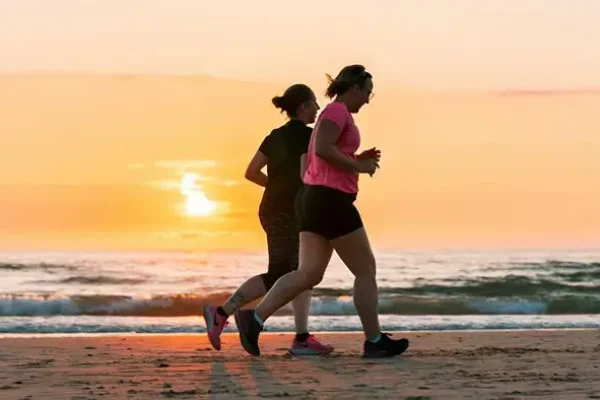 Two people running on the beach at sunset—using movement as a coping strategy for anxiety.